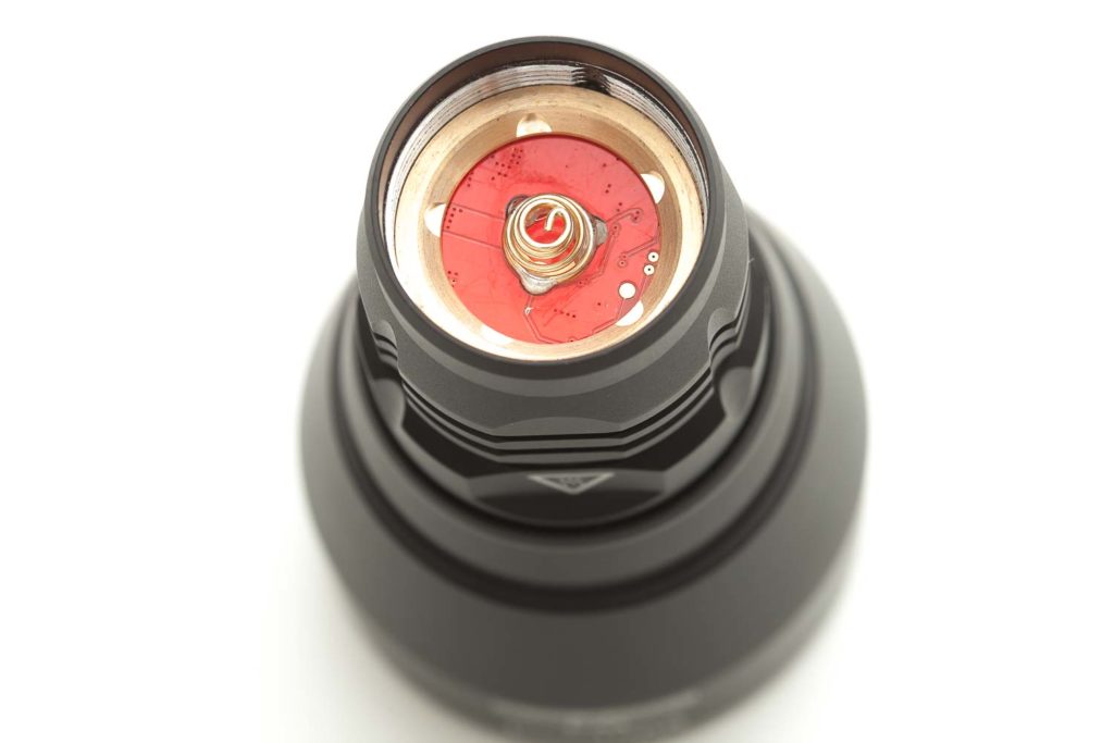 red flashlight driver with copper colored spring